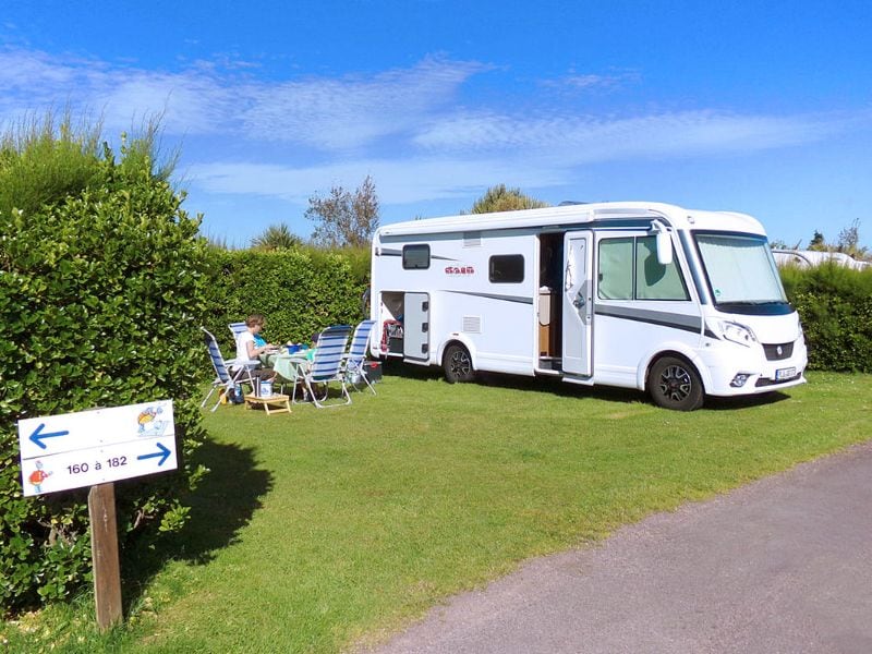 Camping-car avec une femme dans un jardin devant le camping-car.
