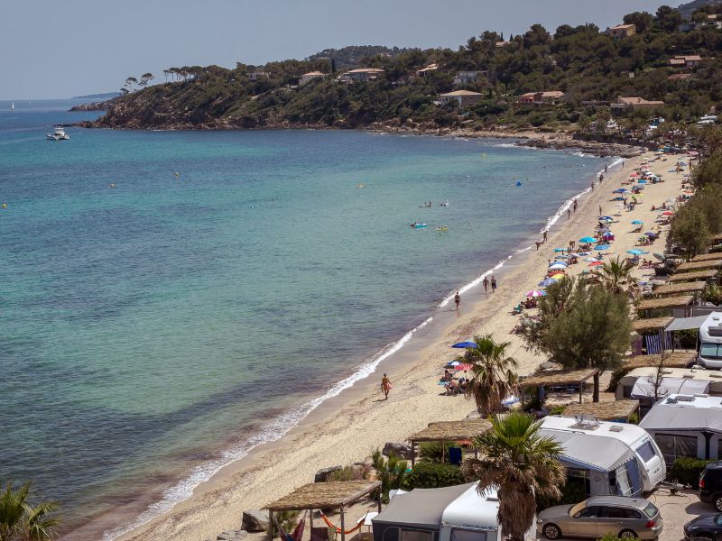 Camp du Domaine : Camping en bord de mer. La mer à gauche, la plage, les campeurs et les caravanes à droite.