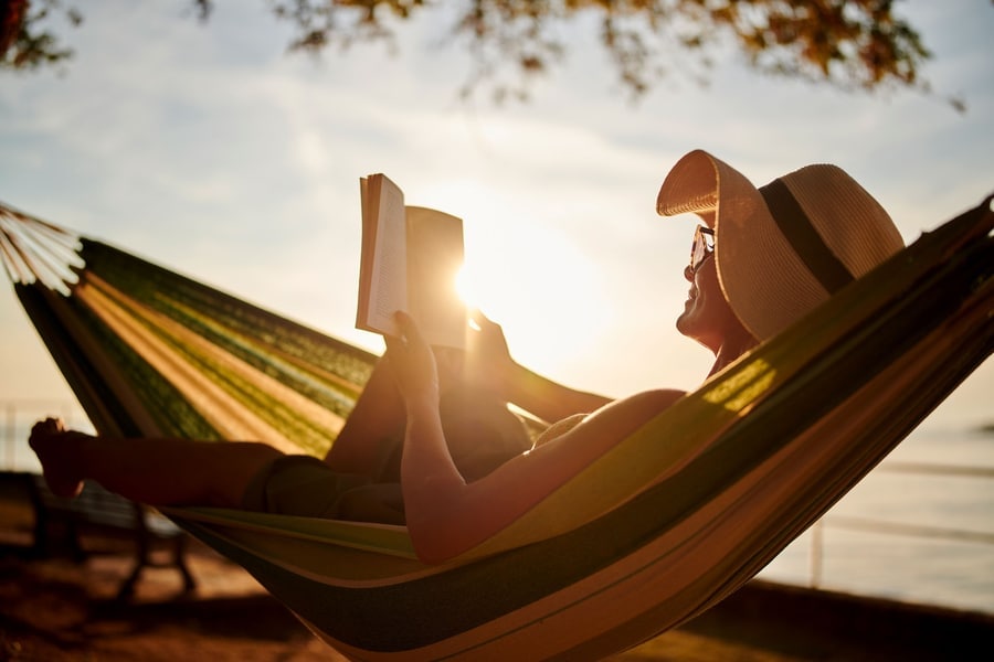 femme lisant un livre dans un hamac